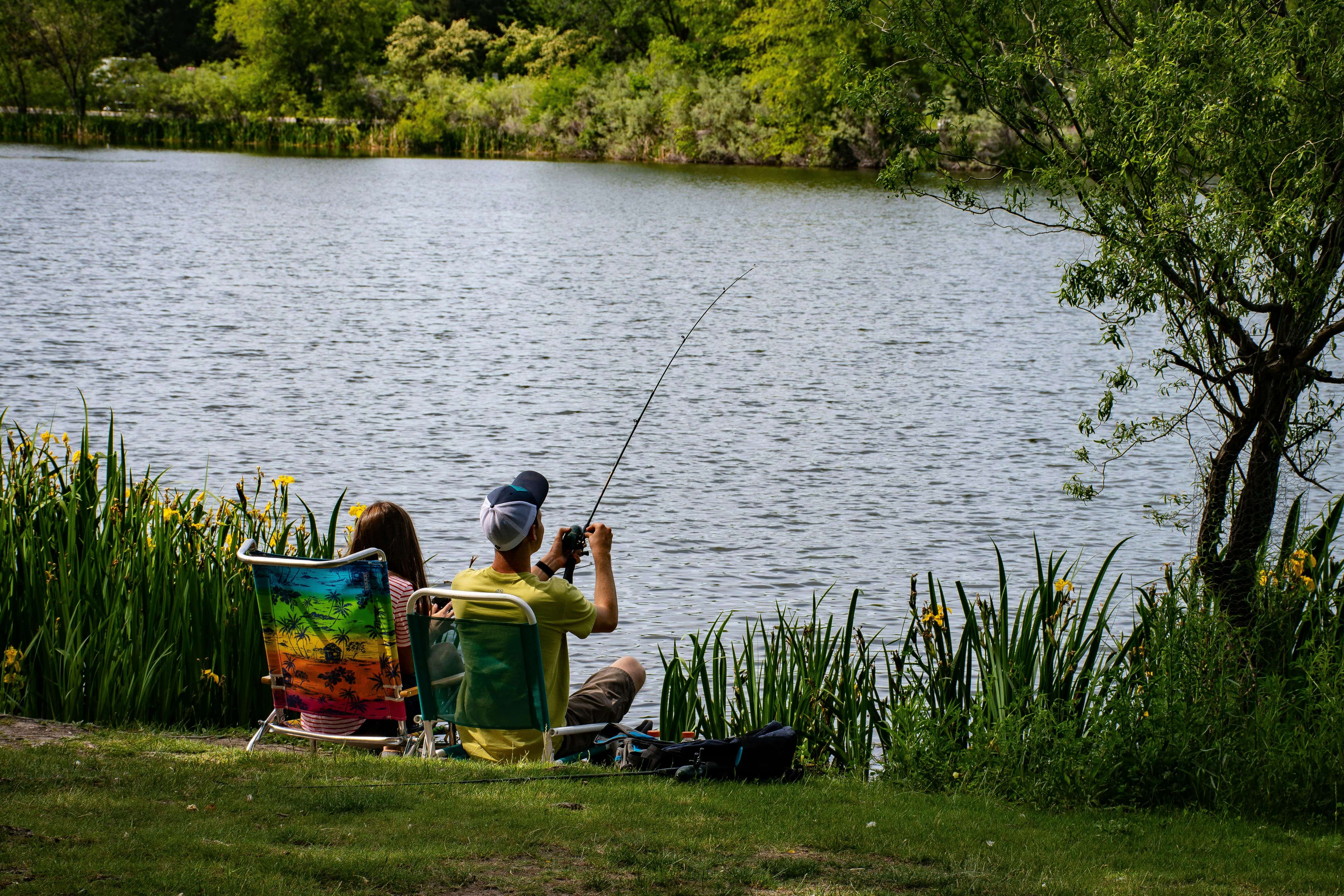 two people fishing by a river