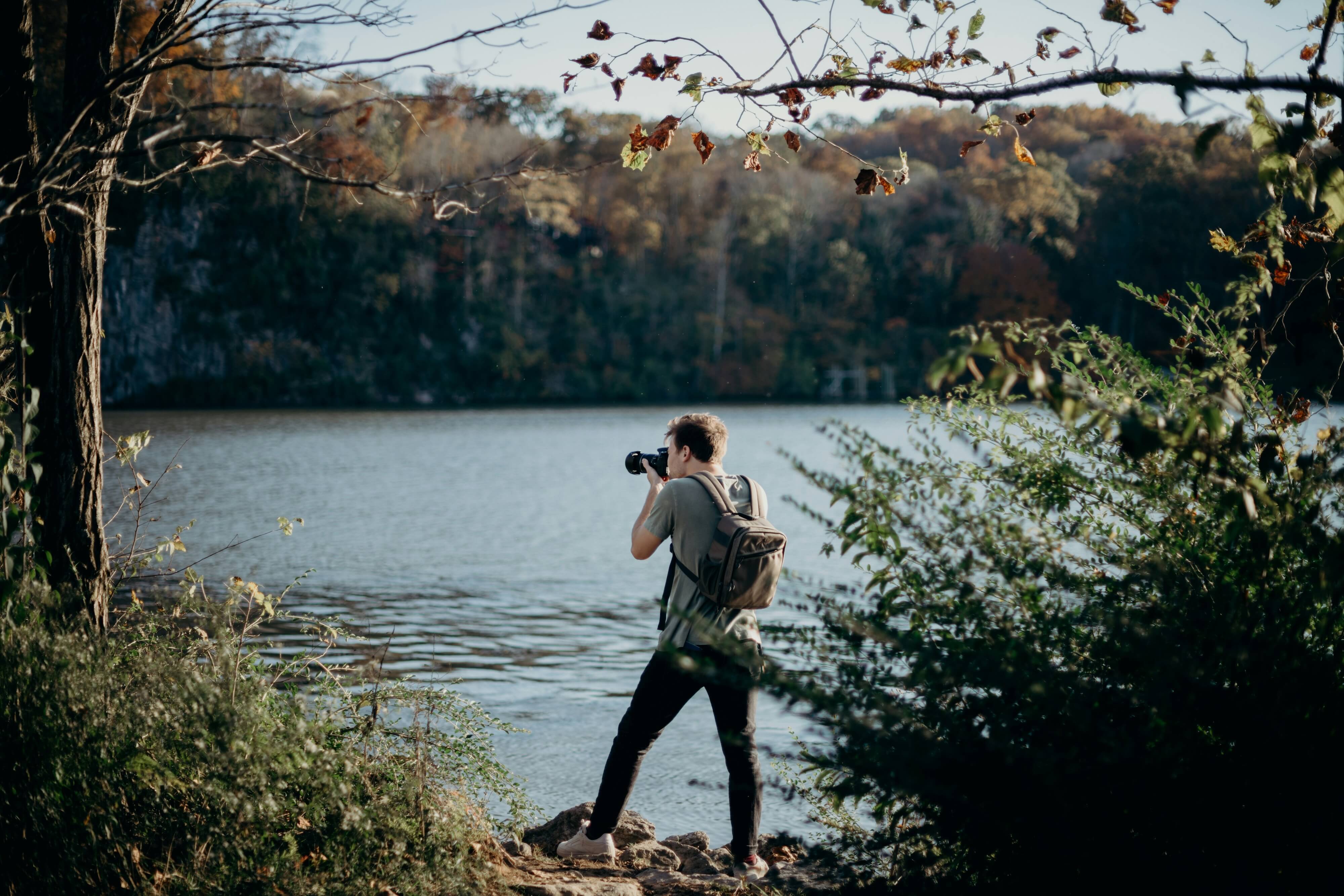 a nature photographer taking a picture by a river