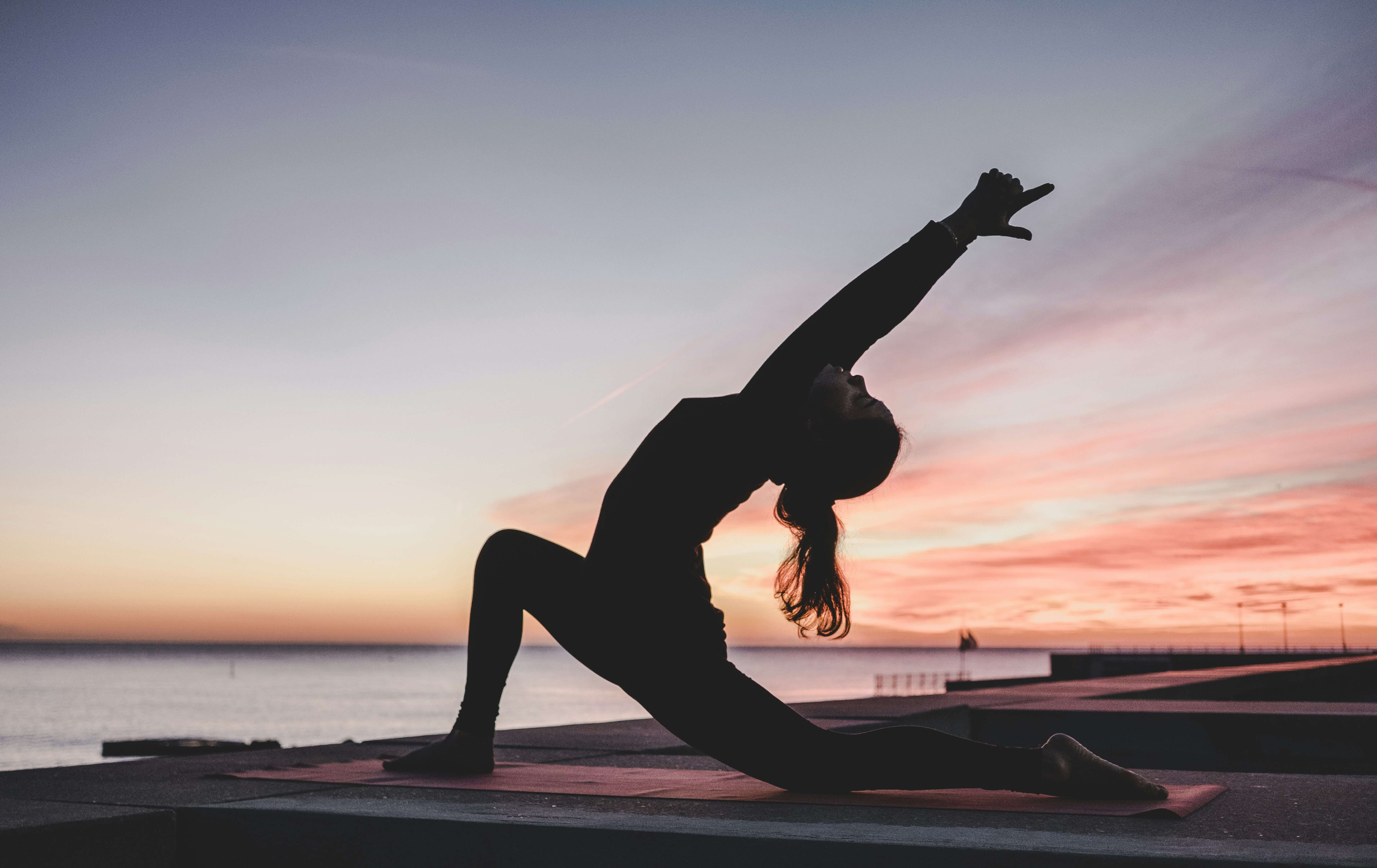 a woman doing a yoga pose outside during sunrise