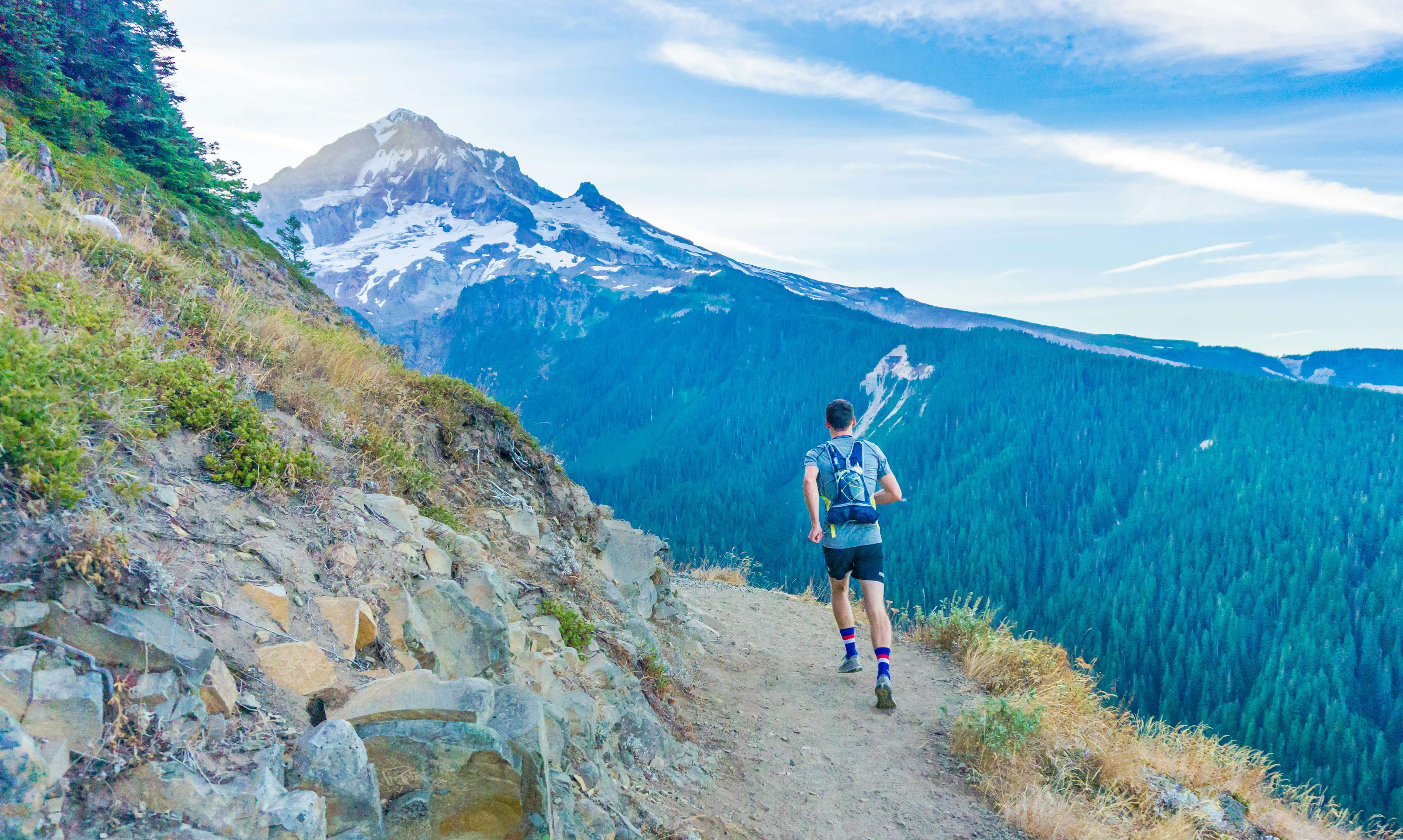 a trail runner running on a trail by a mountain