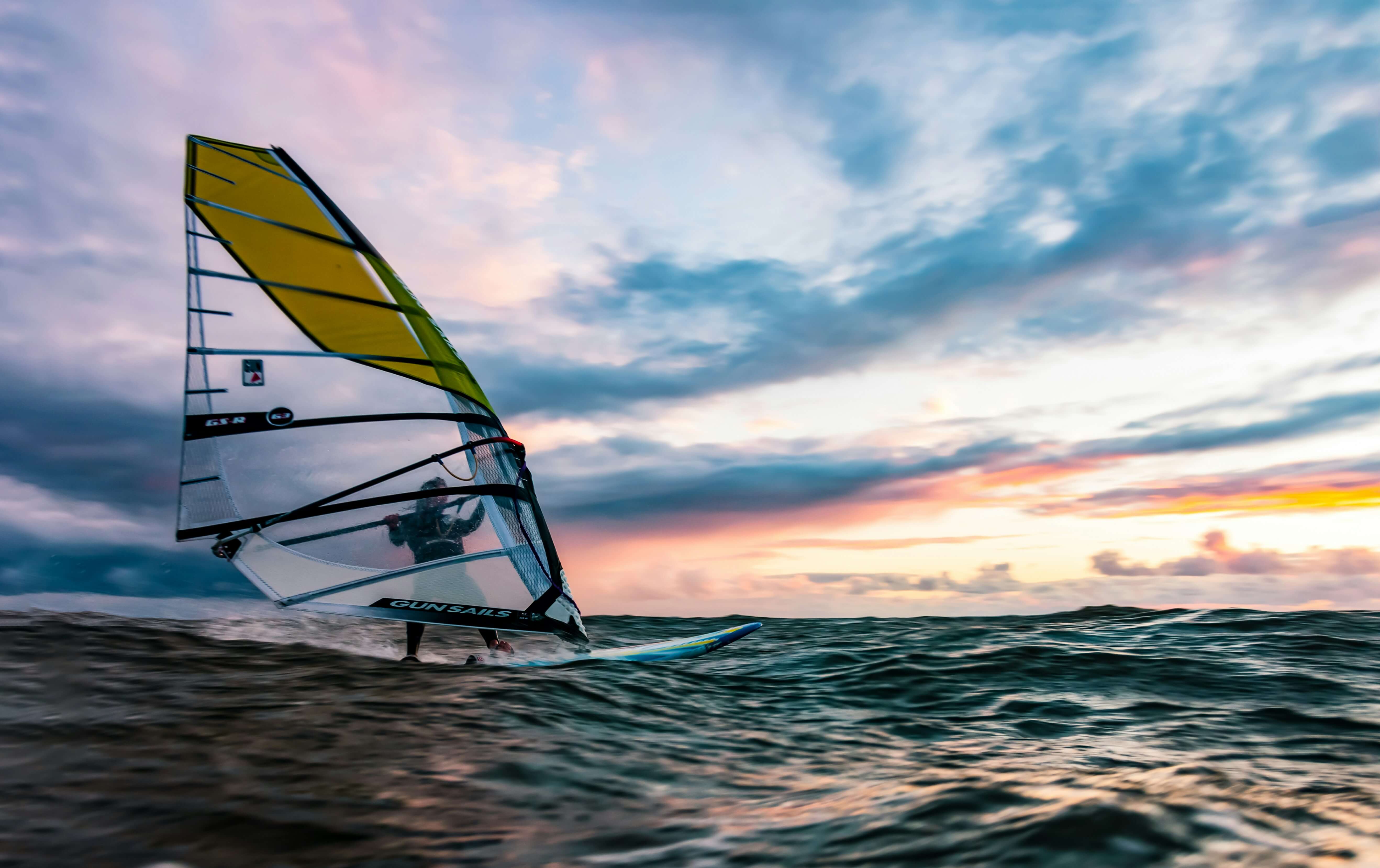 someone windsurfing on the ocean during sunset