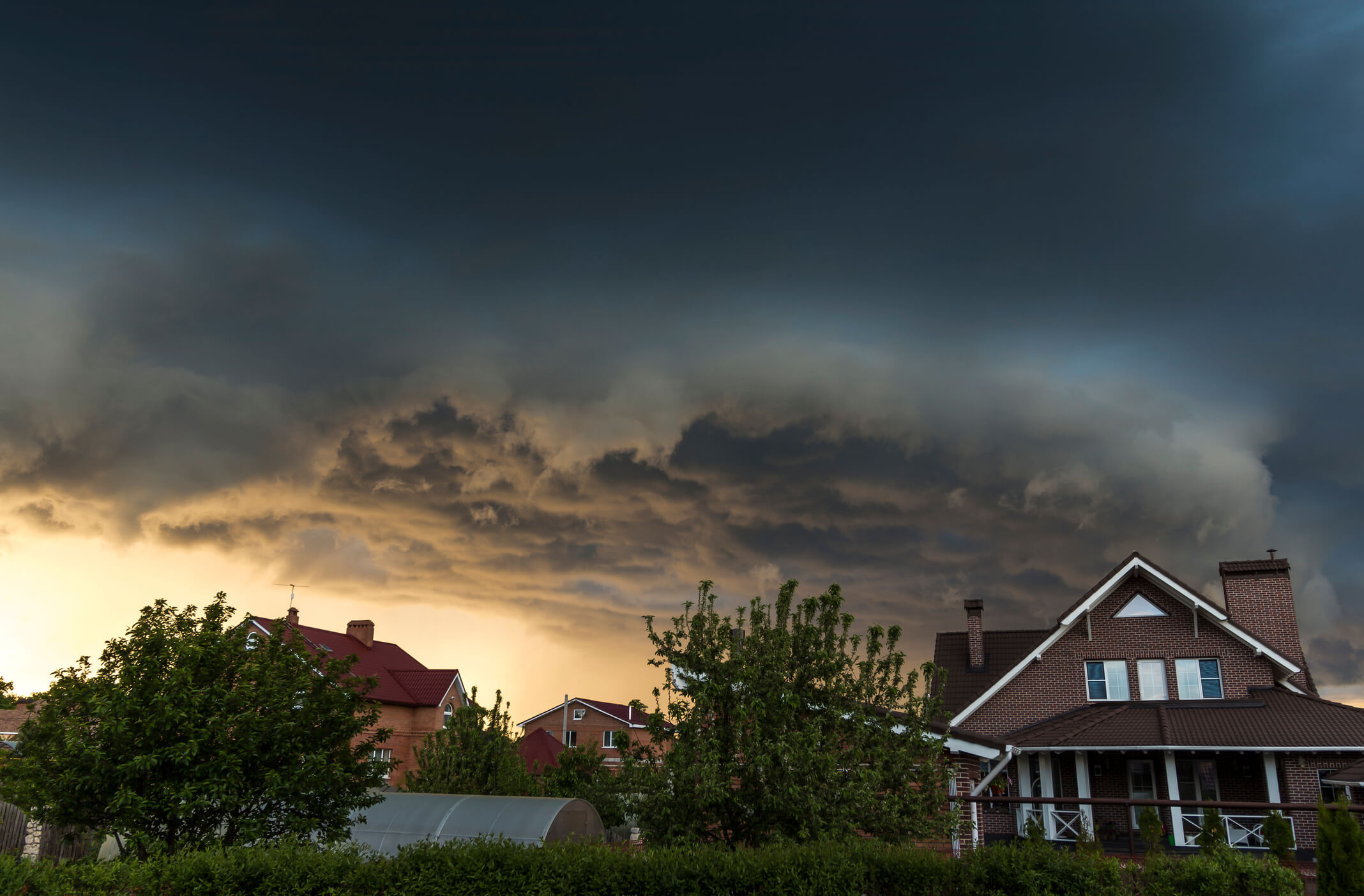 A rainstorm cloud moving toward a residential neighborhood.